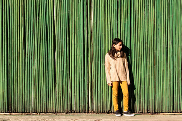 adolescente posando de pie con fondo verde de cañas - obrazy, fototapety, plakaty