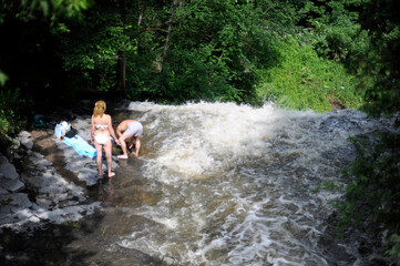 Fototapeta na wymiar un couple se baigne dans une rivière près d'une cascade en été
