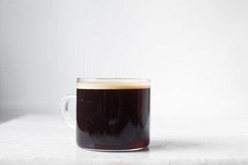 Espresso in a glass cup on a marble tray, foamy top of coffee