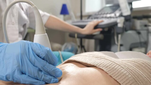 Healthcare concept. Cancer therapy. Ultrasound medical device in stomach examining. Ultrasonis investigation. Closeup shot of young woman lying on hospital bed getting Ultrasound Sonogram Procedure