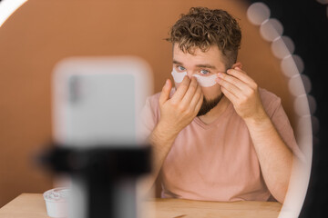 Male beauty blogger doing his make up and recording a video lesson his with mobile phone - vlog,...