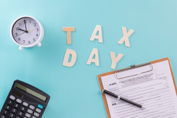 Tax fill concept - 'Tax day' word, clock, pen and calculator  with W-8-BEN form on blue or green backgound color