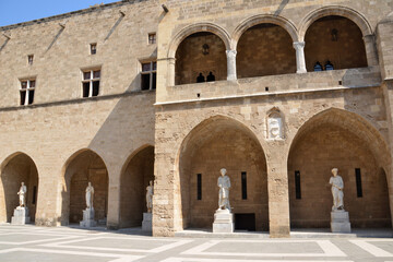 square of medieval castle of Grand Master with sculptures and arches in sunny day, Rhodes island