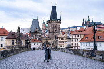 A woman tourist in an overcoat  travels through Prague. A beautiful tourist place. Prague Castle, Czech Republic.
