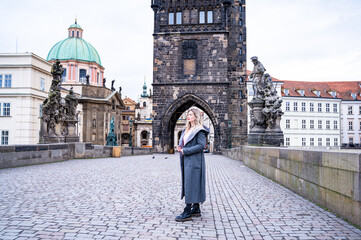 Female tourist walking on the Charles Bridge alone during a foggy morning in Prague, capital of...