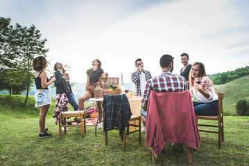 Group of happy friends having fun at the picnic barbecue in a countryside area, celebrating, eating...
