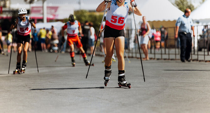 girl skier athlete roller skiing competition on asphalt