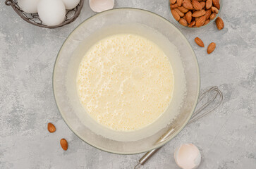 Recipe step by step. The process of making Italian cantucini cookies. Whipped eggs with sugar in a bowl on a gray concrete background. Top view.