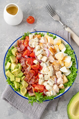 Tradition Cobb salad with fried chicken, avocado, fresh tomatoes, eggs, bacon and cheese on a plate. selective focus