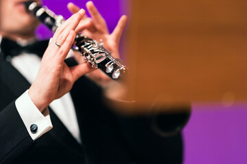 A musician playing the clarinet during a performance dressed in concert black