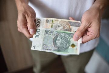 Mężczyzna trzymający banknot 100 i 200 złotowe