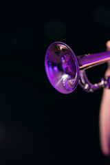 A shiny trumpet bell against a dark background of a performer playing a solo suring a jazz concert