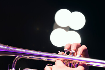 A musician soloing during a jazz gig on a shiny silver plated trumpet with bright stage lights in...