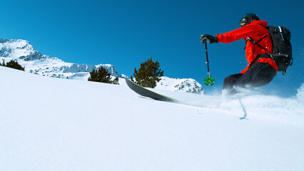Freeride skier riding in the scenic mountains with blue sky