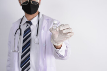 Study of COVID-19 infection. Male doctor examines medicine for illness, man mask with syringe and jar in front