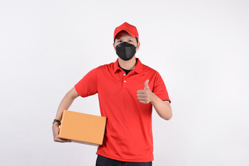 Delivery man employee in red cap blank t-shirt uniform face mask cardboard box isolated on white background. Service quarantine pandemic in front