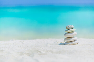 Fototapeta na wymiar Pebble tower on the seaside. Zen concept. Pyramid of stones on sunny beach. Harmony and meditation. Zen stones positive thinking inspirational and relaxation with copy space