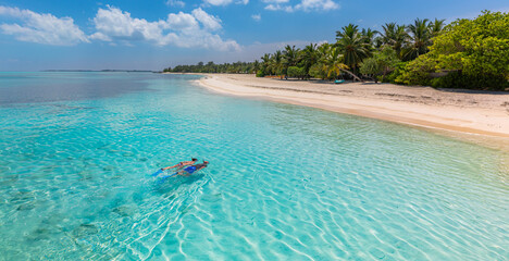 Caucasian couple of tourists snorkel in crystal turquoise water near Maldives Island. Recreational outdoor sport at luxury resort beach scene, calm sea water, couple exotic water, underwater wildlife
