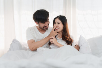 Beautiful asian couple in love and smiling sitting on bed. Romantic moment, relationships, family concept.