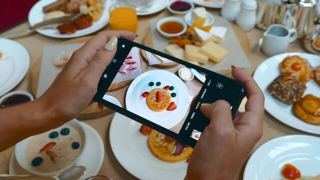 Female influencer and blogger captures breakfast on phone camera.
