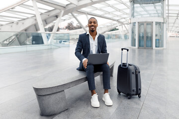 Remote Business. Smiling Black Businessman Working On Laptop While Waiting At Airport