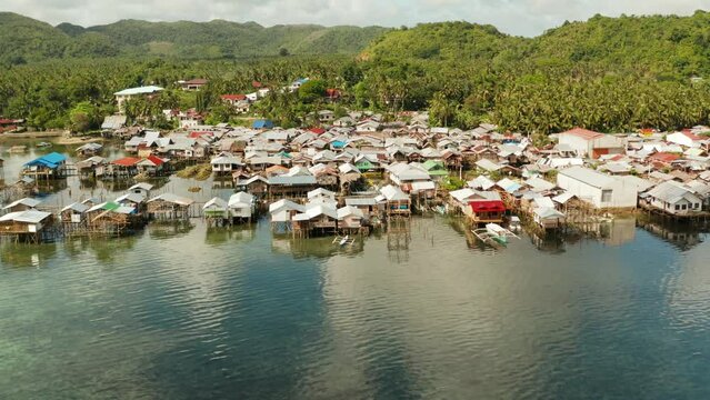Old wooden house standing on the sea in the fishing village, aerial view. Dapa, Siargao, Philippines.
