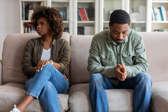 Upset African Man And Woman Sitting On Couch At Home