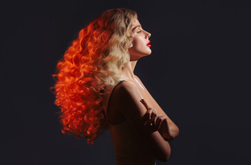 Fashion portrait of blonde woman with curly long hair in colorful light.