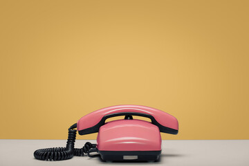 A red retro phone is on the table. Yellow background.