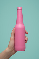 A woman hand holds a pink bottle on a blue background.