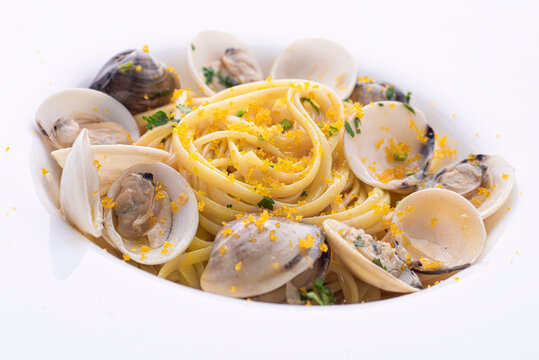 Spaghetti pasta with clams (vongole) and  bottarga (dried tuna or mullet caviar) on a white table. Classic seafood dish of the Sardinia, Sicilli islands and Napoly. Italian healthy cuisine, close up