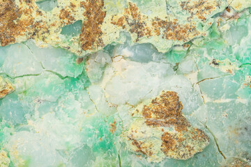 Fototapeta na wymiar Waxy surface of Chrysoprase mineral with visible traces of nickel in apple green parts of the texture