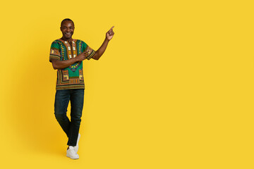 Fototapeta na wymiar Happy african man in traditional shirt pointing at copy space