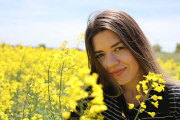 Happy beautiful young woman in yellow canola field.