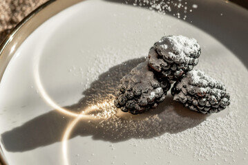 Blackberry berries and the reflection of light in a dish with a golden border. Light pattern on the plate
