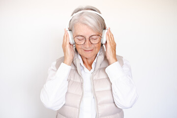 Smiling attractive senior woman closed eyes enjoying music listening songs with headphones on white background.