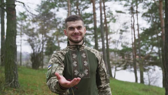 A Military man gives his hand to the camera and smiles. Slow motion shot.