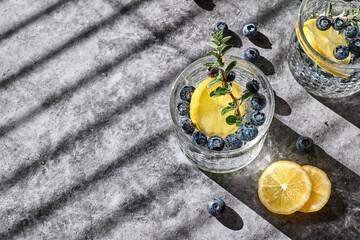 Fresh summer drink blueberry mojito or blueberry icy lemonade with lemon slices, blueberries, ice and thyme.