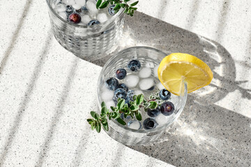 Fresh summer drink blueberry mojito or blueberry icy lemonade with lemon slices, blueberries, ice and thyme.