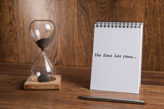 Glass hourglass and notepad with the inscription the time has come