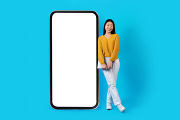 Cool asian lady with laptop standing by big phone, mockup