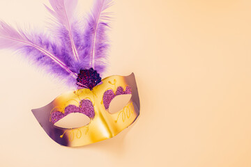 Happy Purim carnival decoration. Top view venetian ball mask with purple feather on pastel...