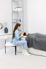 A cosmetic dermatologist works on a patient's skin in a clean, minimalistic white room. The room is bright, tools organized, and the dermatologist's focus reflects her expertise in skin care.