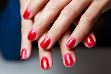 Red manicure with gel polish. Bright manicure in the style of the holiday with foils and sparkles.