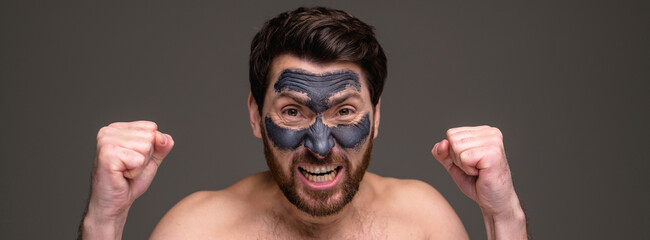 Banner view of annoyed shirtless man with clay mask on face isolated on grey background 