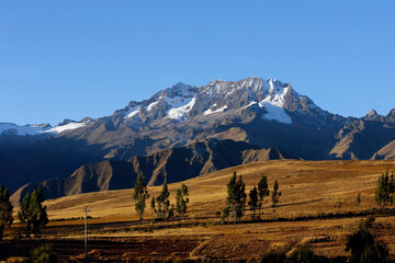Mount Chicon Behind a Green Meadow and Under a Blue Sky. Urubamba Mountain Range, Cusco Region, Peru