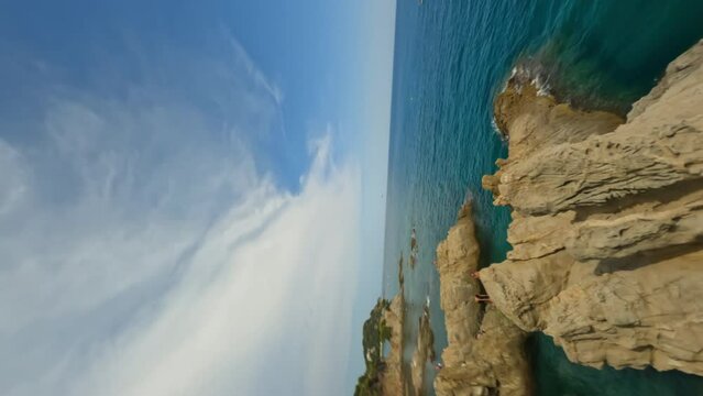 Vertical Dynamic fpv shot down the cliff catching a guy jumping in to water from