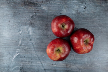 Three red apples above dark blue moody background flat lay