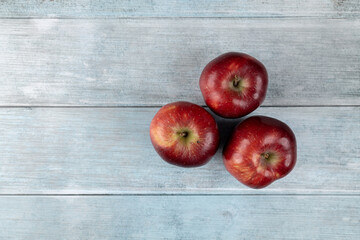 Three red apples above dark blue moody background flat lay