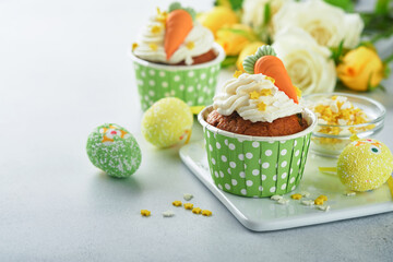 Carrot cake cupcakes for Easter. Carrot cupcakes with cream cheese frosting decorated with tiny...